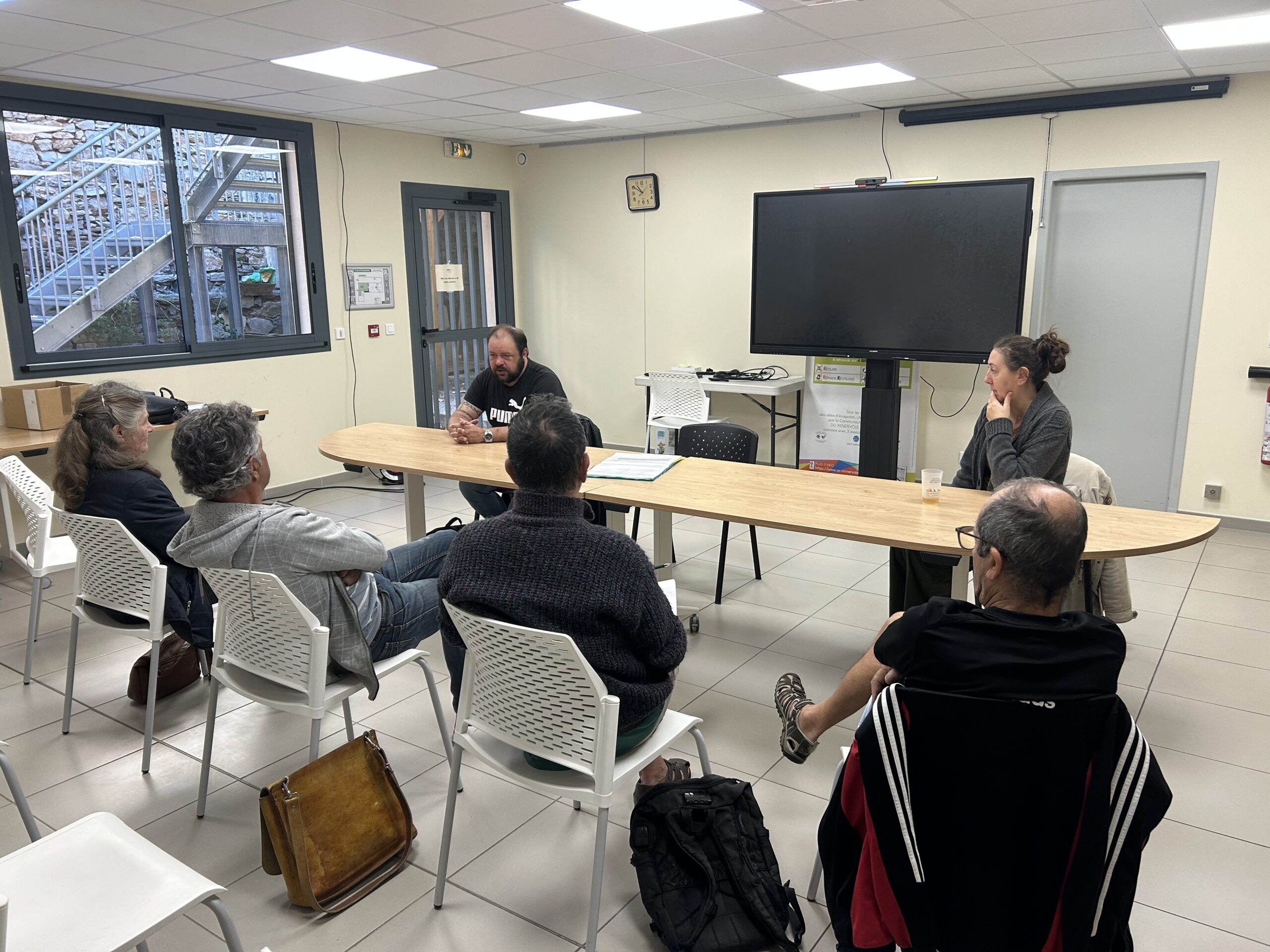 Dans une salle éclairée de réunion, plusieurs personnes sont venus poser des questions à deux techniciens habitat du Pays